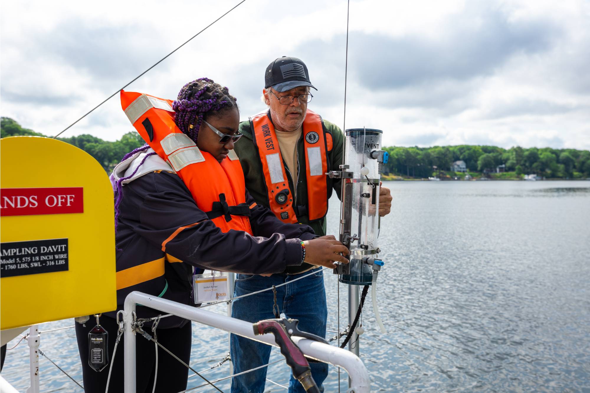 A student and deckhand collect a sample of Spring Lake water during a cruise on the D.J. Angus